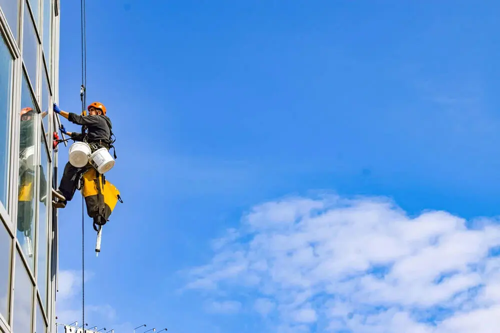 NR 35 - trabalho em altura - trabalhador Limpando a Janela de um edifício usando EPIs.